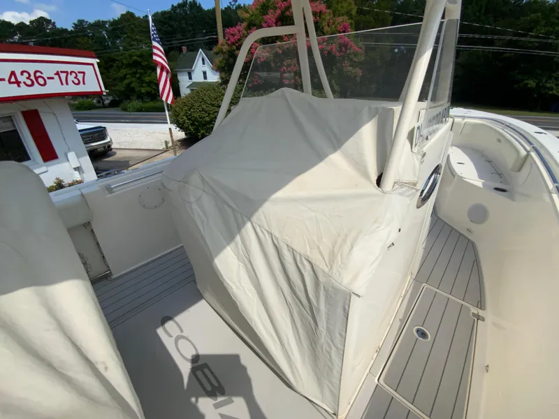 Slide: The Image of 2013 Cobia 296 Center Console boat with covered helm, docked near a flag and building. - 38