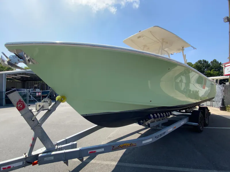 Slide: The Image of 2013 Cobia 296 Center Console boat on trailer, parked outdoors under clear sky. - 5