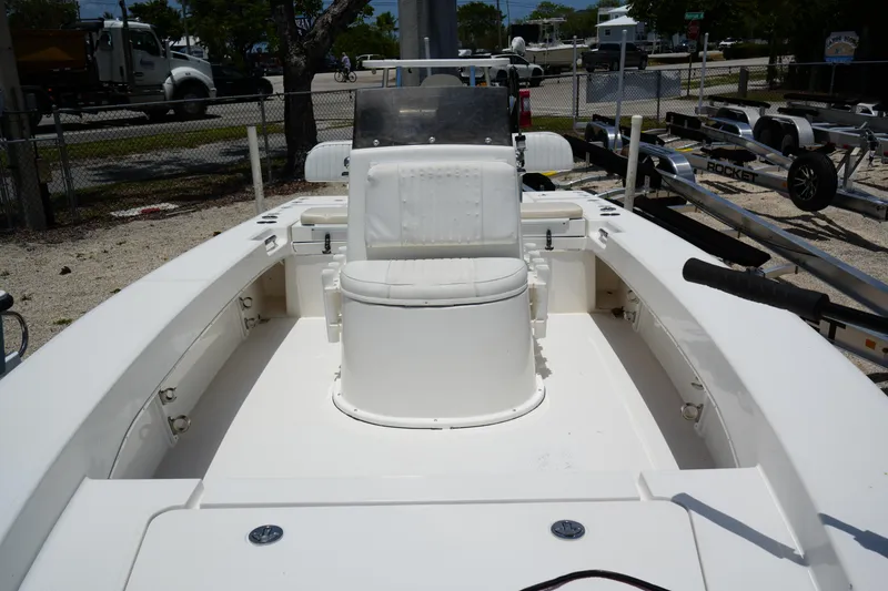 Slide: The Image of 2013 Renegade Nomad 22 boat interior with white seating and console, parked outdoors. - 6