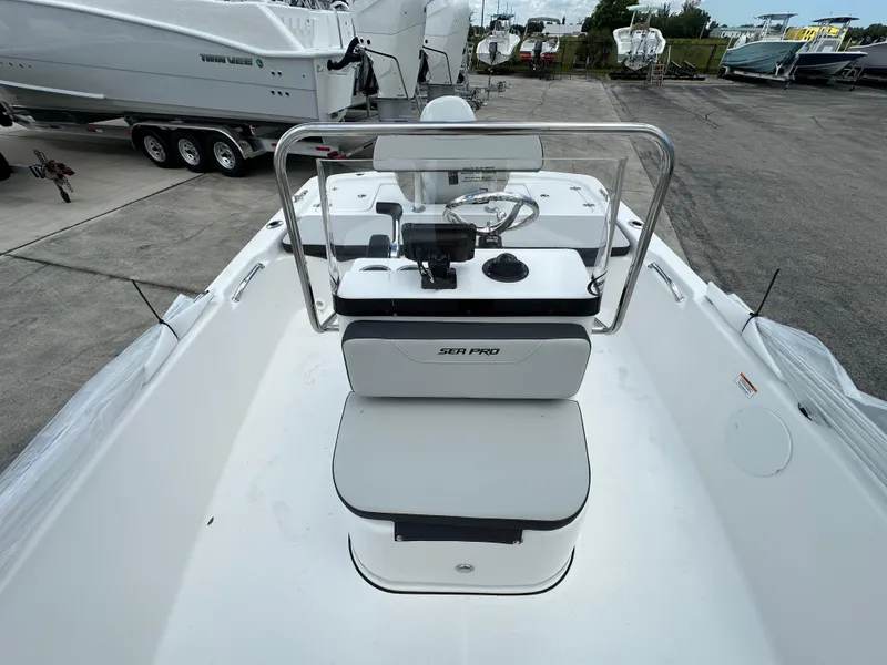 Slide: The Image of 2026 Sea Pro 172 Bay boat interior with steering wheel and seating, parked outdoors. - 7