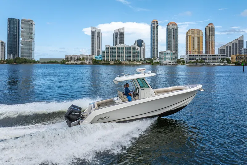 Slide: The Image of 2018 Boston Whaler 280 Outrage cruising on water with city skyline backdrop. - 13