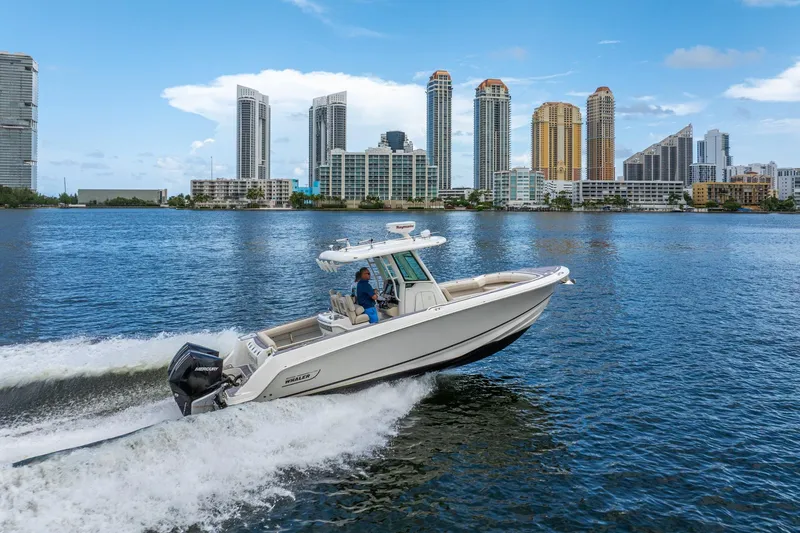 Slide: The Image of 2018 Boston Whaler 280 Outrage cruising on water with city skyline backdrop. - 14