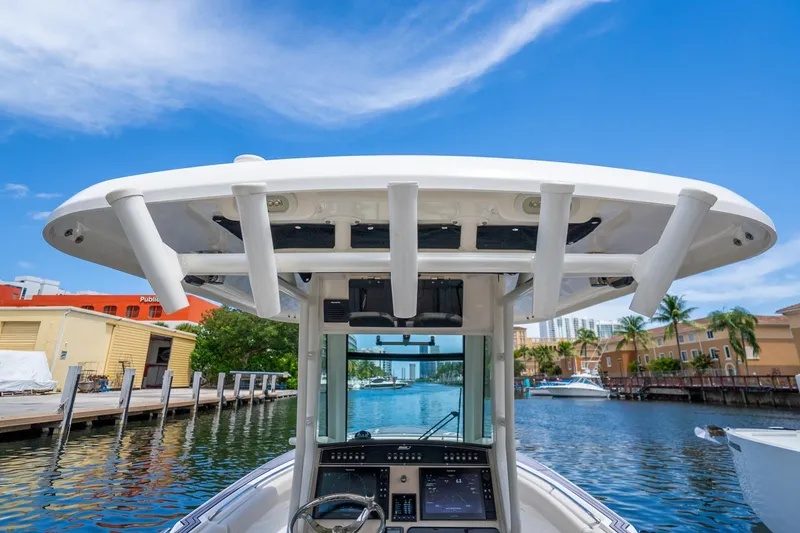 Slide: The Image of 2018 Boston Whaler 280 Outrage boat console with rod holders, docked in a scenic marina. - 18