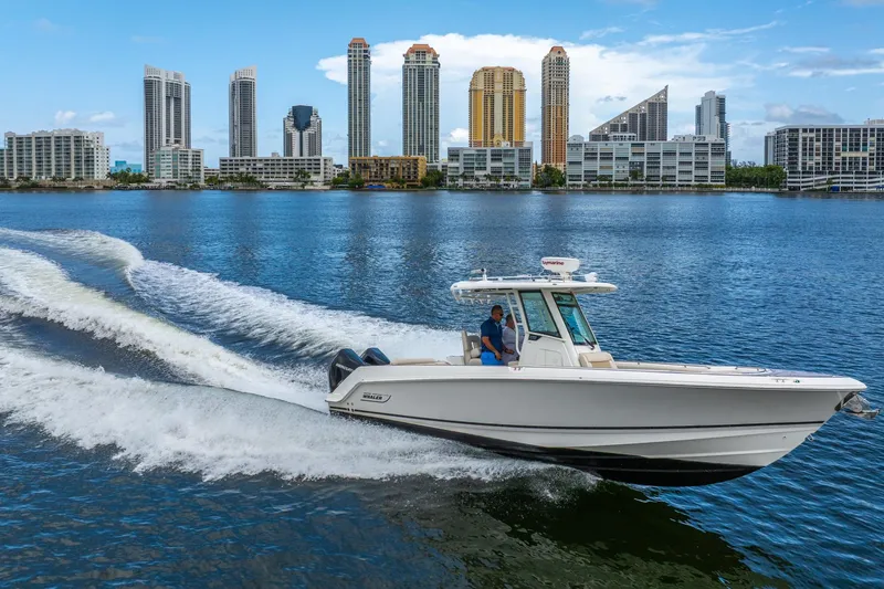 Slide: The Image of 2018 Boston Whaler 280 Outrage cruising on water with city skyline backdrop. - 2