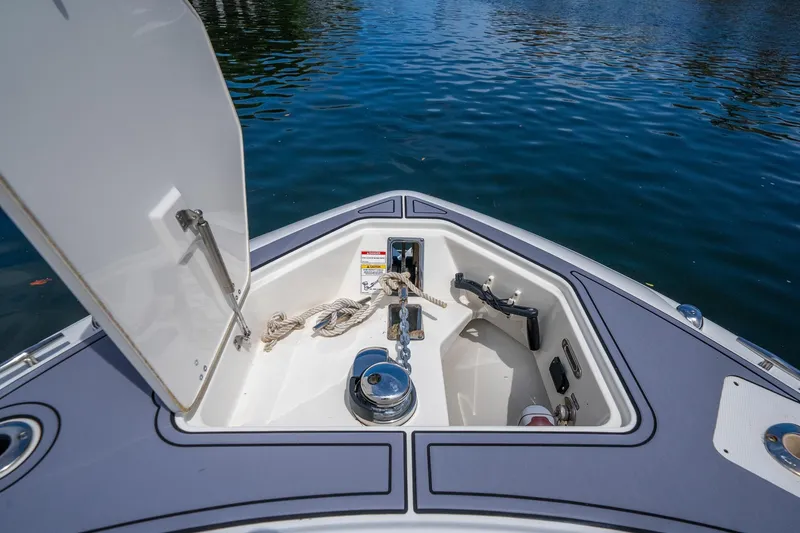 Slide: The Image of 2018 Boston Whaler 280 Outrage anchor compartment with open hatch, docked on calm water. - 30