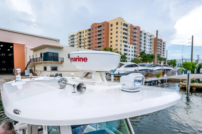 Slide: The Image of 2018 Boston Whaler 280 Outrage docked near marina with modern buildings in background. - 38