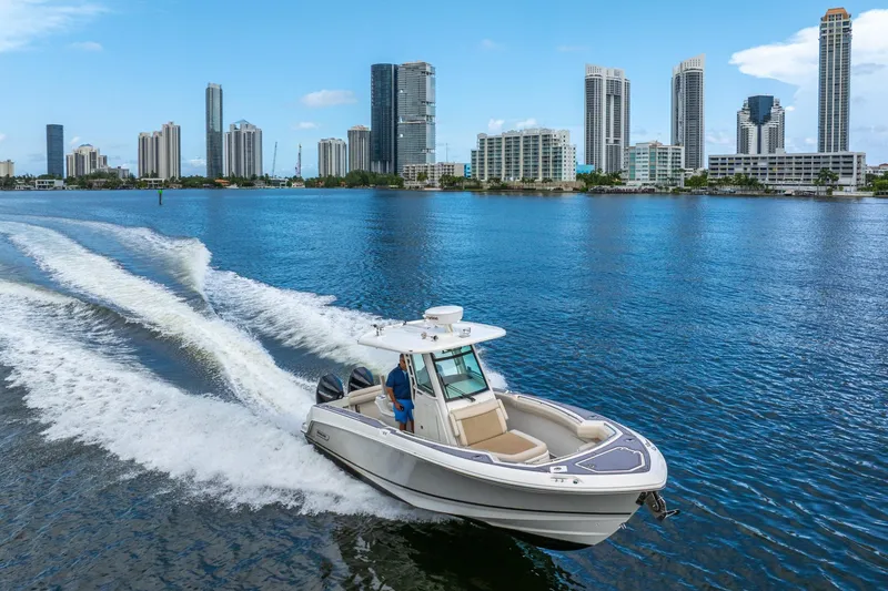 Slide: The Image of 2018 Boston Whaler 280 Outrage cruising on water with city skyline backdrop. - 5