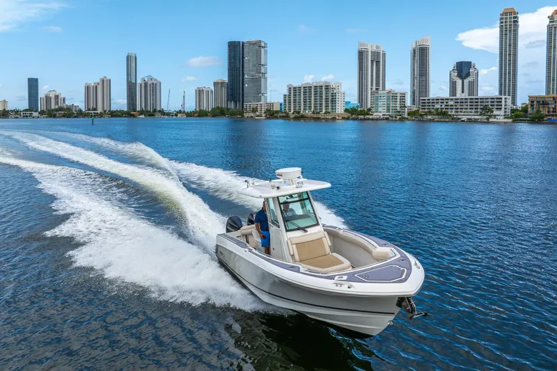 Slide: The Image of 2018 Boston Whaler 280 Outrage cruising on water with city skyline backdrop. - 7