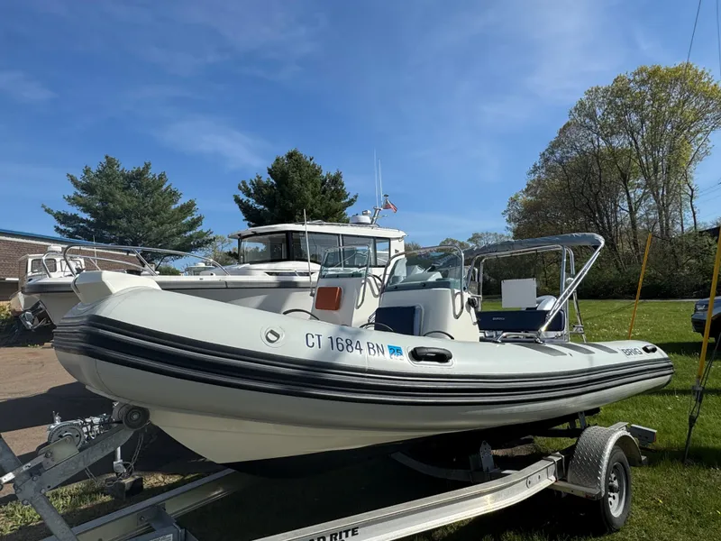 Slide: The Image of 2023 Brig Navigator 485 boat on trailer, parked outdoors under clear blue sky. - 1