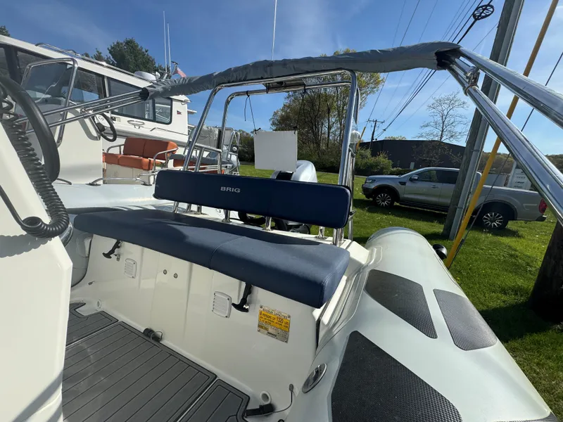 Slide: The Image of 2023 Brig Navigator 485 boat interior with seating and canopy, parked outdoors. - 5