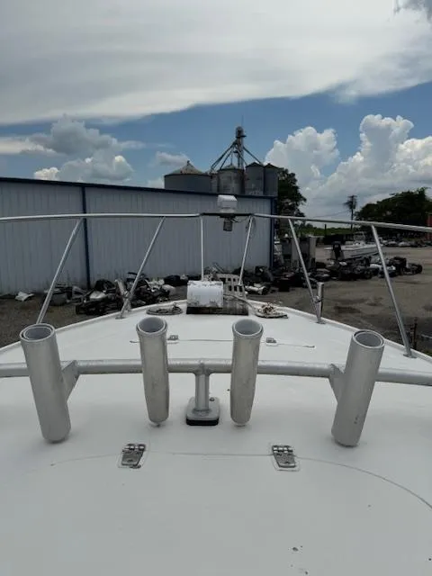 Slide: The Image of 1986 Blackfin 27 boat bow with rod holders, docked near industrial buildings under cloudy sky. - 14