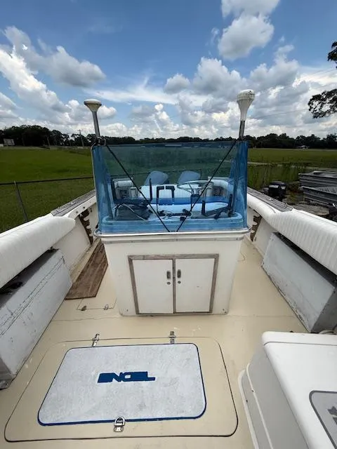 Slide: The Image of 1986 Blackfin 27 boat deck with blue windshield, white seating, and storage compartments under a cloudy sky. - 15