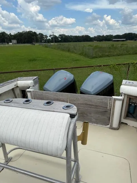 Slide: The Image of 1986 Blackfin 27 boat with dual outboard motors, docked in a grassy area under a cloudy sky. - 23
