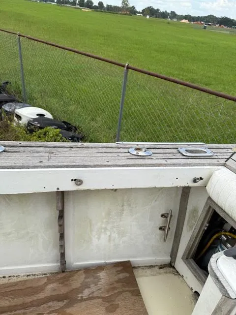 Slide: The Image of 1986 Blackfin 27 boat interior with weathered wood, near a grassy field and chain-link fence. - 25