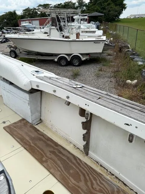 Slide: The Image of 1986 Blackfin 27 boat interior with visible wear, parked near another boat on a trailer. - 26