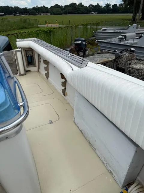 Slide: The Image of 1986 Blackfin 27 boat interior with white seating and outboard motor, docked outdoors. - 3