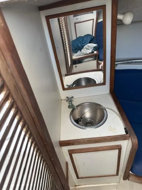 Slide: The Image of 1986 Blackfin 27 boat interior with sink, mirror, and blue seating. - 8