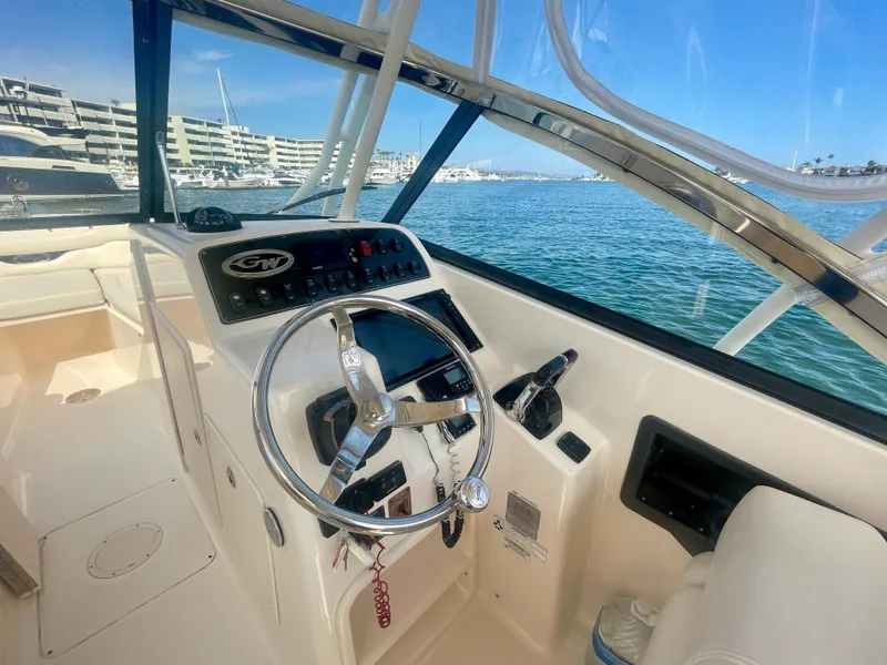 Slide: The Image of 2015 Grady-White 275 Freedom boat helm with steering wheel and controls, docked in marina. - 18