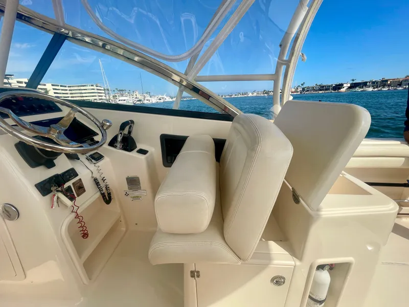 Slide: The Image of 2015 Grady-White 275 Freedom boat interior with steering wheel and seating, docked by marina. - 22