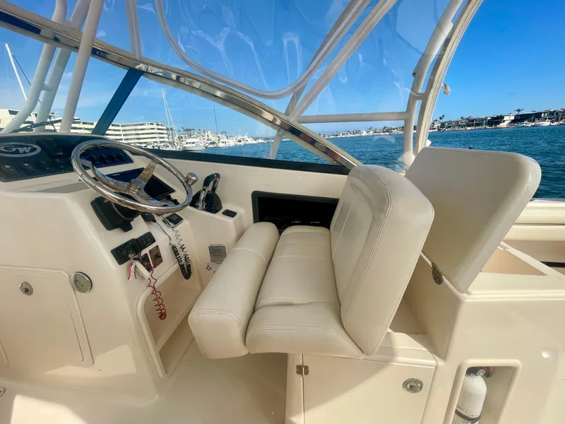 Slide: The Image of 2015 Grady-White 275 Freedom boat interior with steering wheel and seating, docked by the marina. - 23