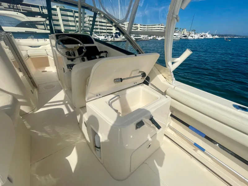 Slide: The Image of 2015 Grady-White 275 Freedom boat interior with open storage, steering wheel, and ocean view. - 24
