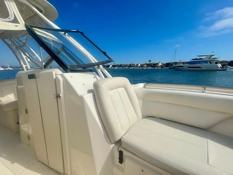 Slide: The Image of 2015 Grady-White 275 Freedom boat interior with seating, overlooking marina and blue sky. - 3