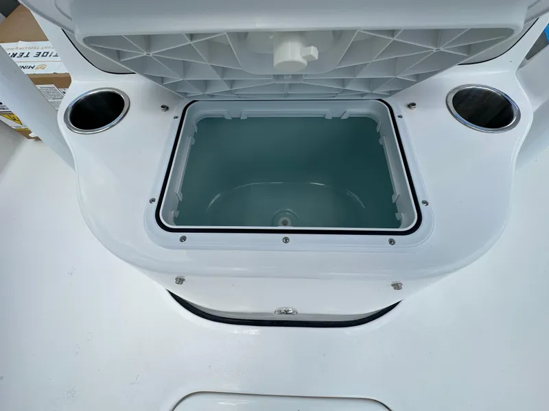 Slide: The Image of 2026 Sea Pro 230 Bay boat storage compartment with cup holders, open lid view. - 12