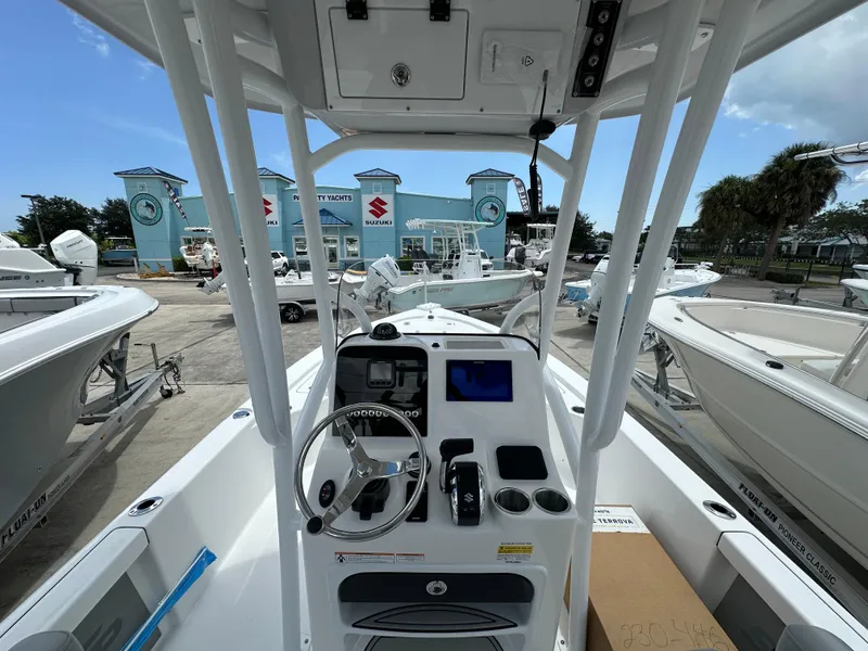 Slide: The Image of 2026 Sea Pro 230 Bay boat dashboard with steering wheel and controls at a marina. - 5