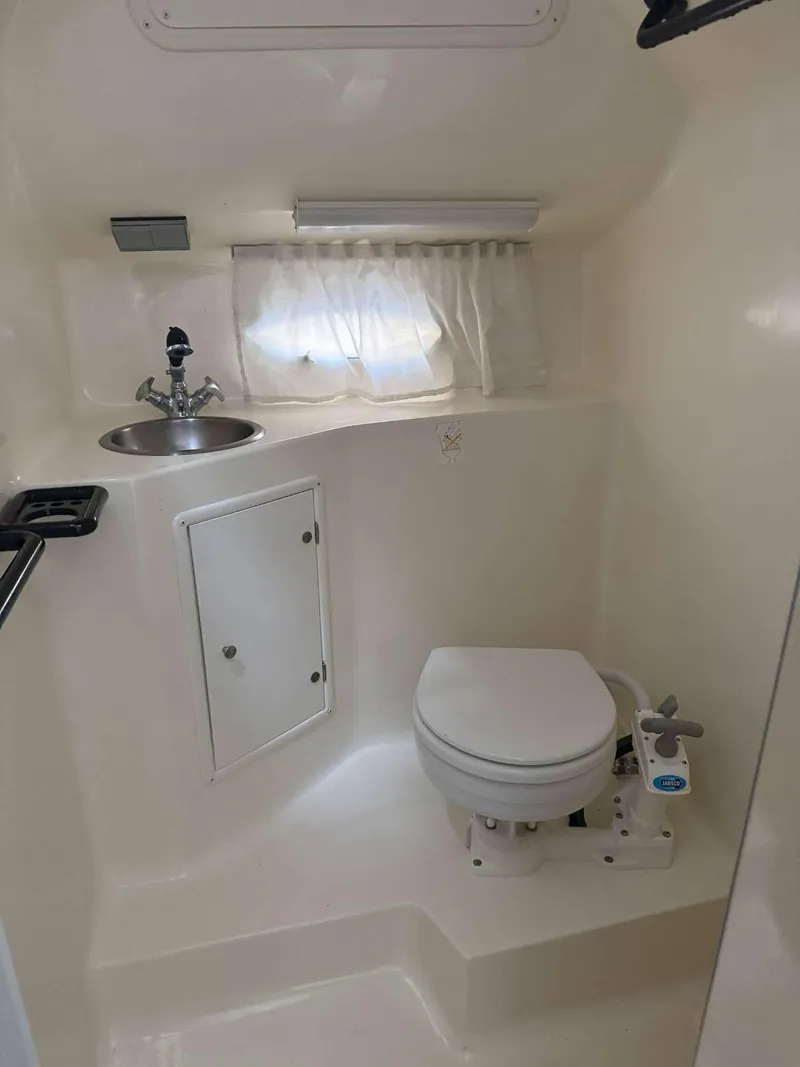 Slide: The Image of 1996 Rinker 280 Fiesta Vee boat bathroom with sink, toilet, and storage cabinet. - 12