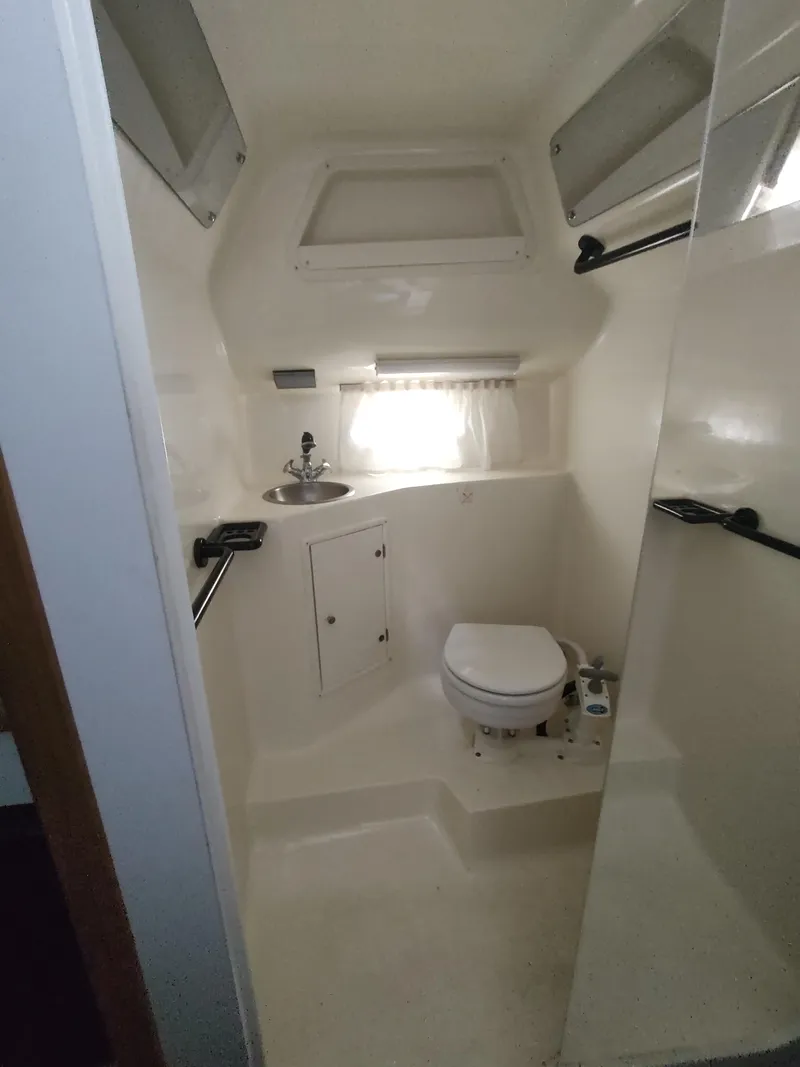 Slide: The Image of 1996 Rinker 280 Fiesta Vee boat bathroom with sink, toilet, and storage cabinet. - 16