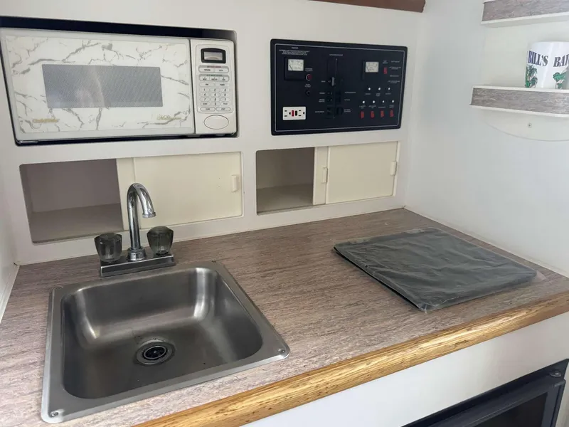 Slide: The Image of 1996 Rinker 280 Fiesta Vee boat kitchenette with sink, microwave, and control panel. - 8