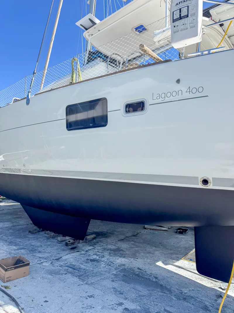 Slide: The Image of 2011 Lagoon 400 catamaran on dry dock, showcasing sleek hull design. - 65