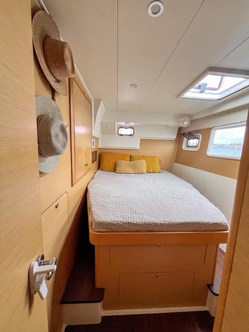 Slide: The Image of Cozy bedroom interior of 2011 Lagoon 400 catamaran with natural wood finish and porthole windows. - 9