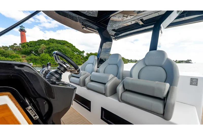 Slide: The Image of 2024 Pardo Yachts 43 helm with luxury seating, steering wheel, and scenic lighthouse view. - 31