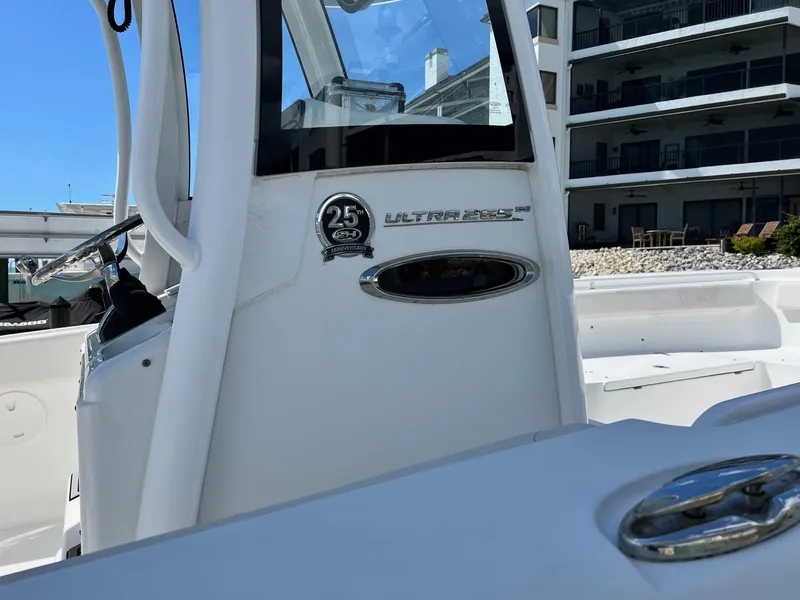 Slide: The Image of 2021 Sea Hunt Ultra 265 SE boat, featuring 25th anniversary emblem, docked near modern building. - 7