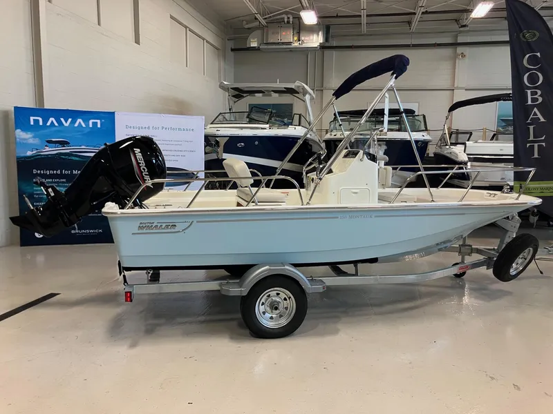 Slide: The Image of 2026 Boston Whaler 150 Montauk boat on trailer in showroom. - 3