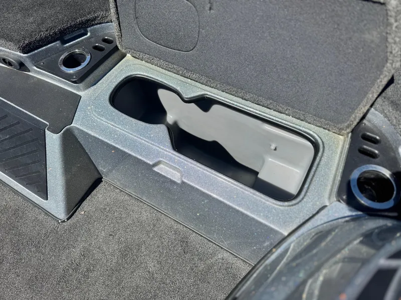 Slide: The Image of 2017 Tracker Nitro Z19 boat storage compartment with cup holders and carpeted interior. - 16