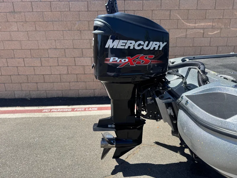 Slide: The Image of 2017 Tracker Nitro Z19 with Mercury Pro XS outboard motor, parked near a brick wall. - 6
