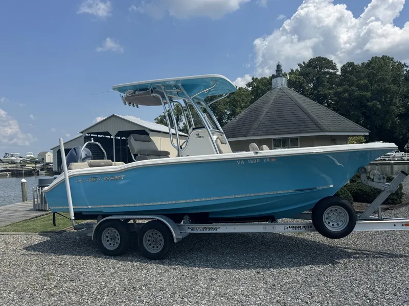 The Image of 2023 Key West 219 FS boat on trailer, parked near marina under cloudy sky. - 1
