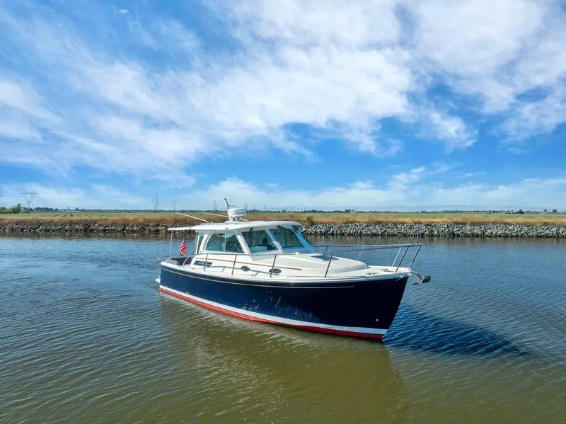 Slide: The Image of 2018 Back Cove 32 boat cruising on a calm river under a clear blue sky. - 19