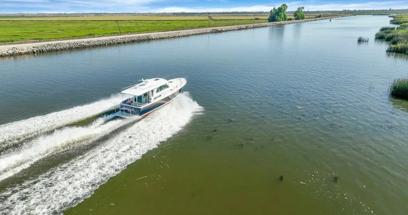 Slide: The Image of 2018 Back Cove 32 cruising on a serene river with lush green banks. - 2