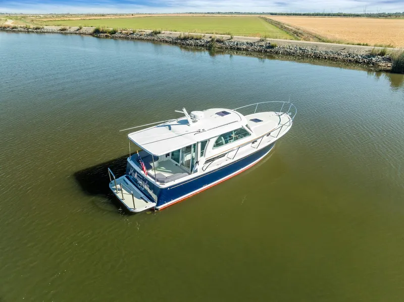 Slide: The Image of 2018 Back Cove 32 boat on calm water, surrounded by scenic landscape. - 26