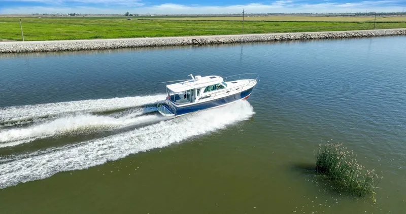 Slide: The Image of 2018 Back Cove 32 cruising on a calm river with lush green banks. - 3
