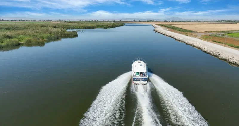 Slide: The Image of 2018 Back Cove 32 cruising on a serene river under a clear blue sky. - 35