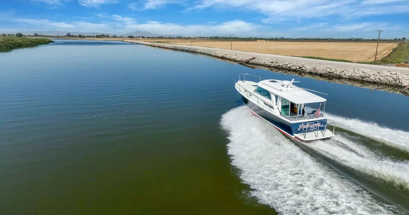 Slide: The Image of 2018 Back Cove 32 cruising on a serene river under a clear blue sky. - 36
