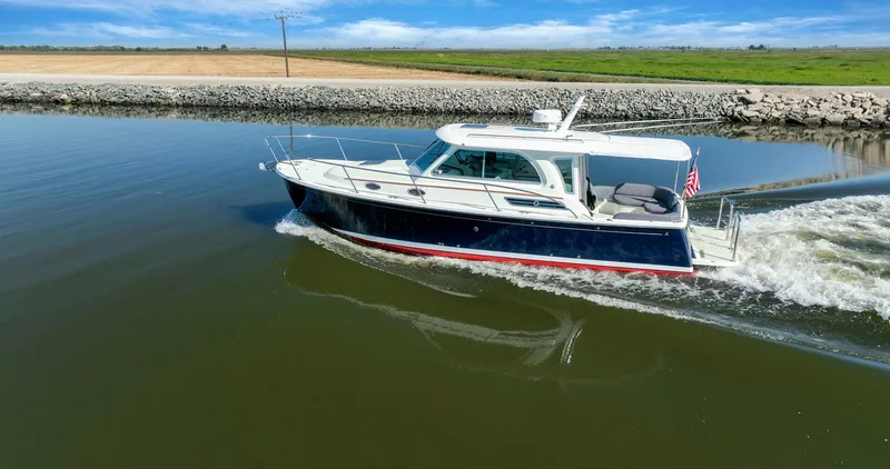 Slide: The Image of 2018 Back Cove 32 cruising on a calm river with scenic countryside backdrop. - 37