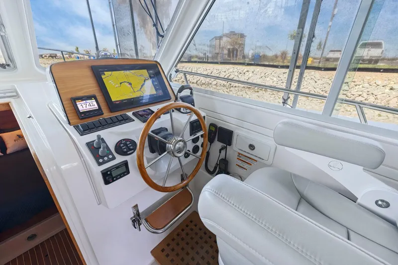 Slide: The Image of 2018 Back Cove 32 helm with navigation display, wooden steering wheel, and comfortable seating. - 45