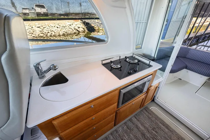 Slide: The Image of 2018 Back Cove 32 yacht interior with kitchenette, featuring stove, sink, and seating area. - 48