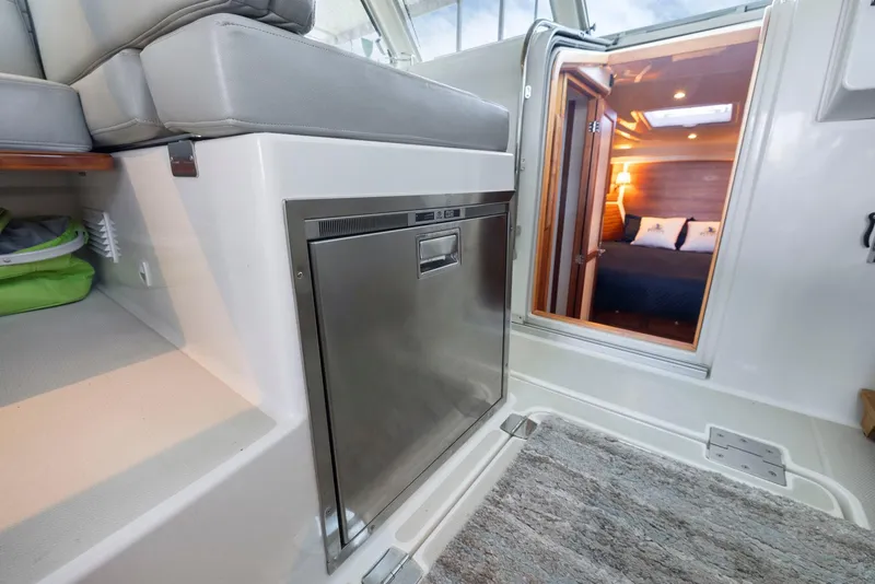 Slide: The Image of Interior of 2018 Back Cove 32 boat, featuring a stainless steel fridge and cozy cabin entrance. - 49