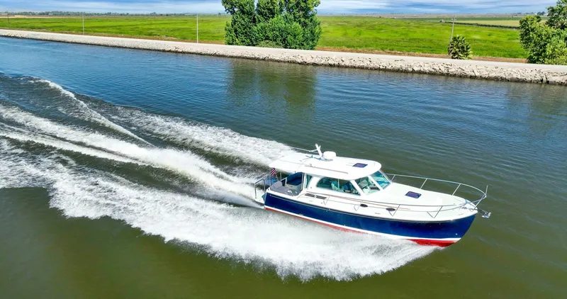 Slide: The Image of 2018 Back Cove 32 cruising on a calm river, leaving a wake behind. - 5